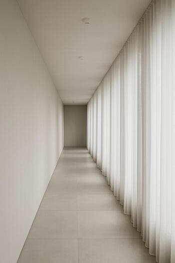 Uzun koridorda tam duvar boyunca uzanan tül perde